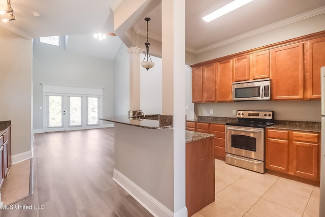 kitchen with decorative light fixtures, vaulted ceiling, dark stone countertops, ornamental molding, and appliances with stainless steel finishes