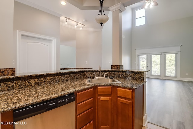 kitchen with stainless steel dishwasher, pendant lighting, track lighting, dark stone countertops, and sink