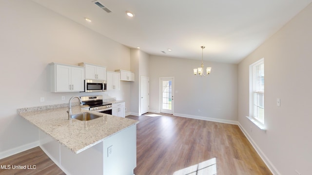 7876 Gardendale Dr, Olive Branch, MS 38654 - kitchen with stainless steel appliances, plenty of natural light, white cabinets, light wood-type flooring, and high vaulted ceiling