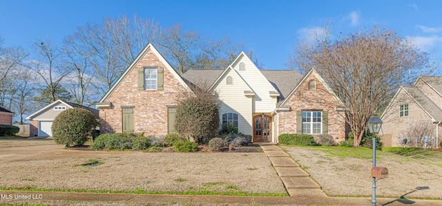 tudor home with a garage, an outdoor structure, and a front yard