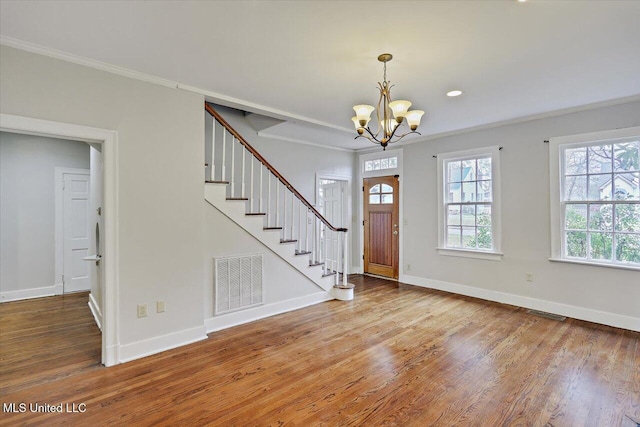 foyer entrance featuring visible vents, baseboards, stairway, wood finished floors, and crown molding