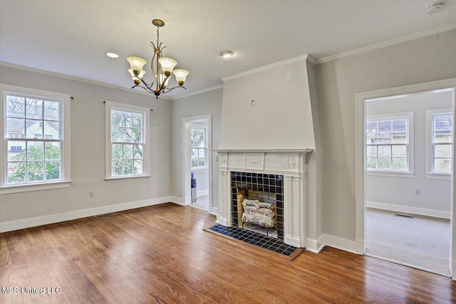 unfurnished living room featuring crown molding, visible vents, a tiled fireplace, wood finished floors, and baseboards