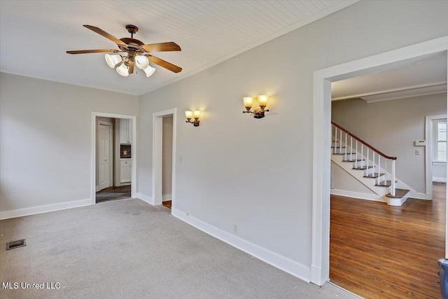 unfurnished room with ceiling fan, visible vents, baseboards, ornamental molding, and stairway