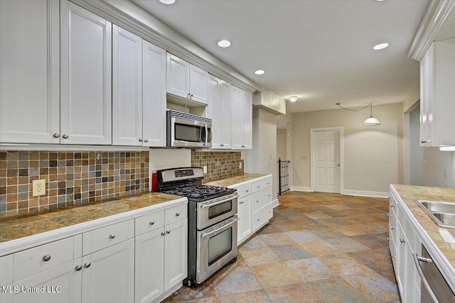 kitchen with decorative light fixtures, backsplash, appliances with stainless steel finishes, white cabinetry, and baseboards