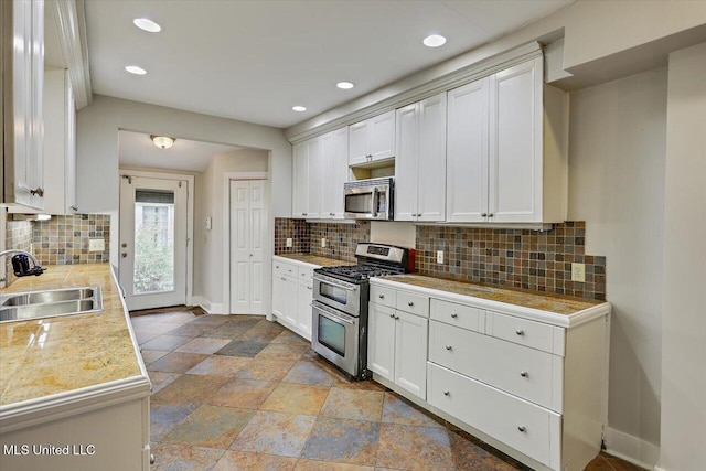 kitchen featuring white cabinets, tile counters, stainless steel appliances, and a sink