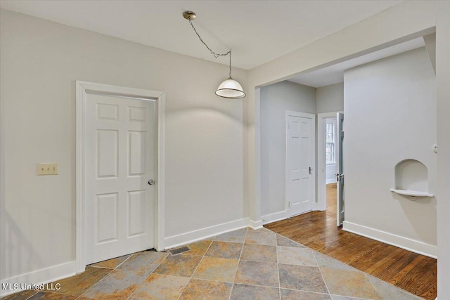 unfurnished dining area featuring baseboards and wood finished floors