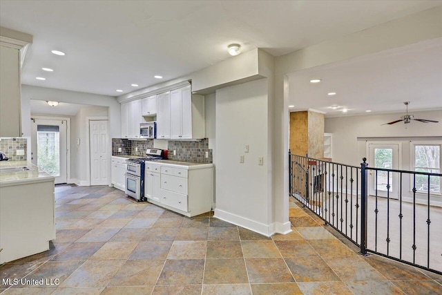 kitchen with stainless steel appliances, a sink, white cabinetry, light countertops, and tasteful backsplash