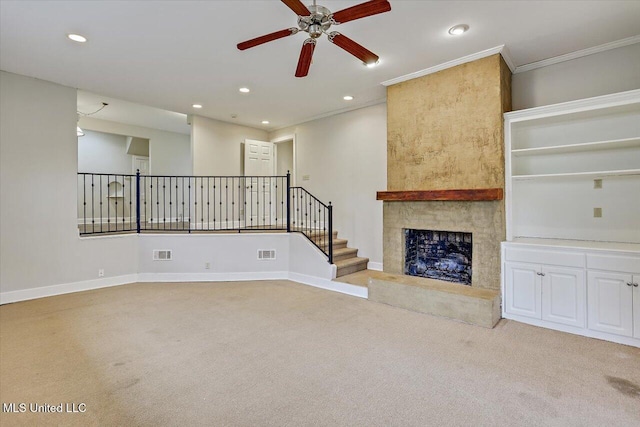 unfurnished living room with a large fireplace, light carpet, crown molding, and visible vents