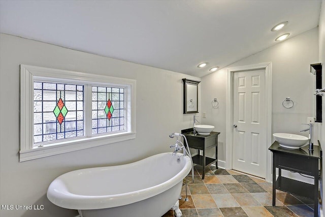 bathroom featuring lofted ceiling, a freestanding tub, vanity, and recessed lighting