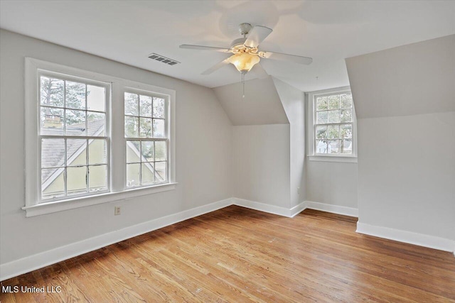 additional living space featuring ceiling fan, light wood-style flooring, visible vents, baseboards, and vaulted ceiling