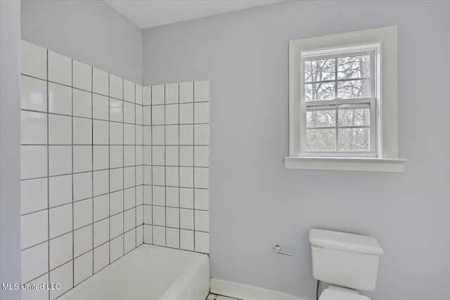 bathroom featuring baseboards, toilet, and a bathing tub