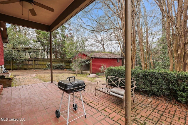 view of patio / terrace with a storage shed, a ceiling fan, a grill, a fenced backyard, and an outdoor structure