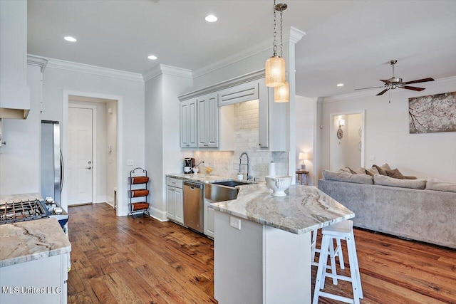 kitchen featuring light stone countertops, wood-type flooring, a kitchen bar, stainless steel appliances, and pendant lighting