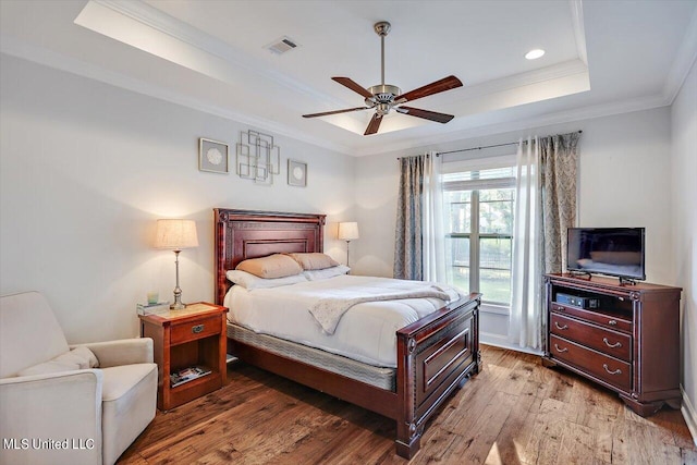 bedroom featuring crown molding, a raised ceiling, hardwood / wood-style flooring, and ceiling fan