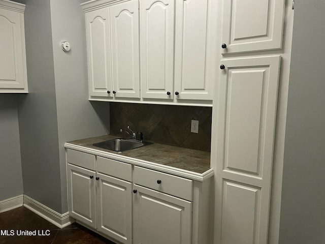 kitchen featuring white cabinets, backsplash, and sink