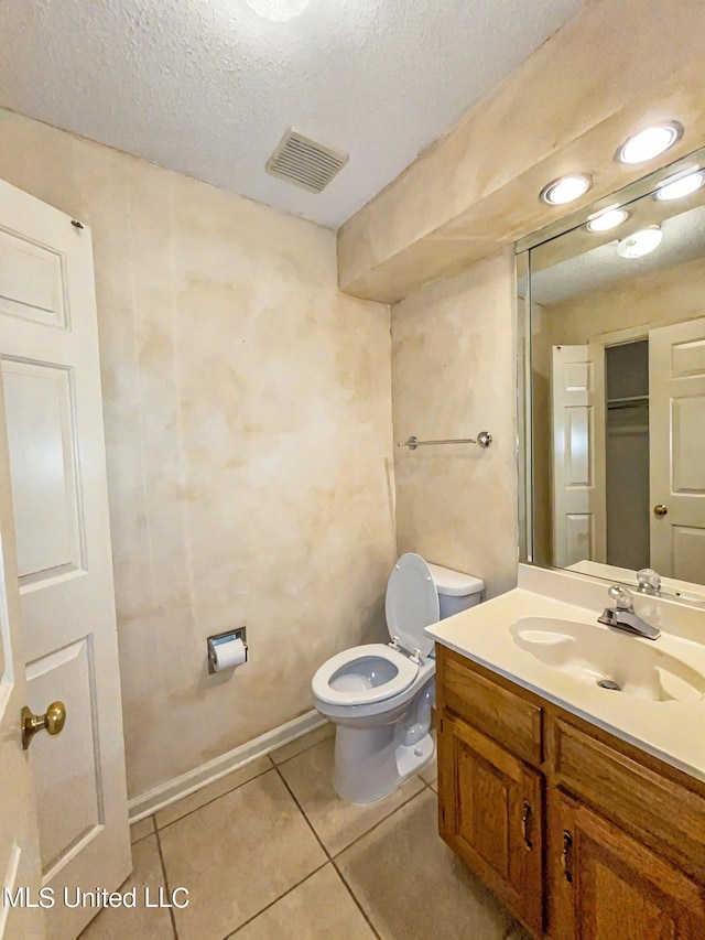 bathroom featuring vanity, toilet, tile patterned floors, and a textured ceiling