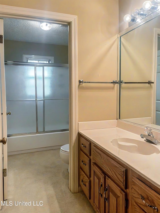 full bathroom with vanity, toilet, a textured ceiling, and combined bath / shower with glass door