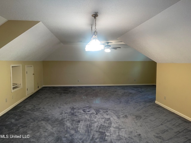 bonus room featuring dark carpet, vaulted ceiling, a textured ceiling, and ceiling fan