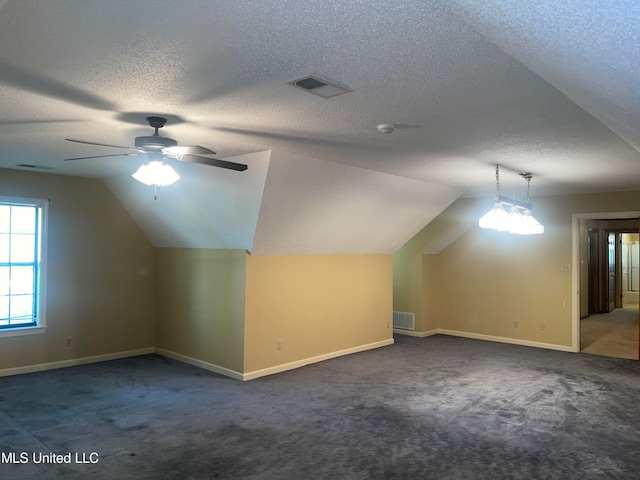 bonus room with a textured ceiling, dark carpet, and vaulted ceiling