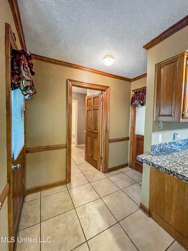 kitchen featuring ornamental molding, a textured ceiling, and light tile patterned floors