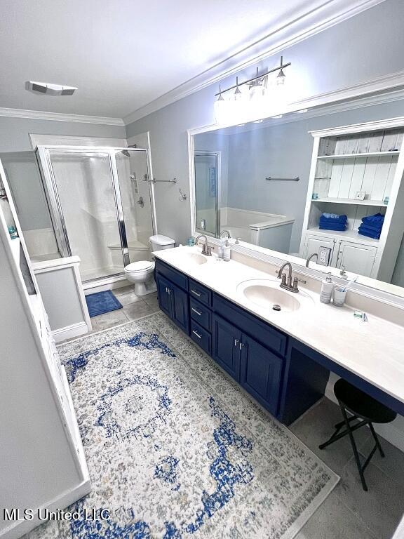 full bathroom with a stall shower, toilet, crown molding, and a sink