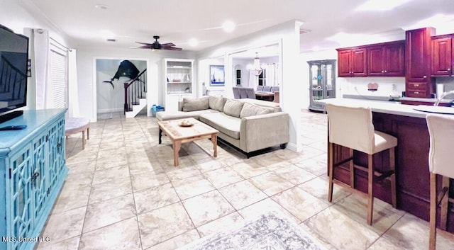 living room featuring baseboards, stairs, and ceiling fan