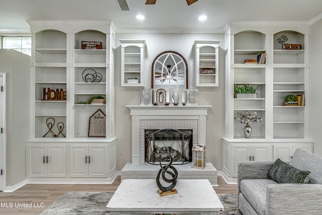 living room with ornamental molding, a brick fireplace, and light wood-type flooring