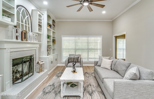 living room featuring ceiling fan, ornamental molding, light hardwood / wood-style flooring, and a fireplace