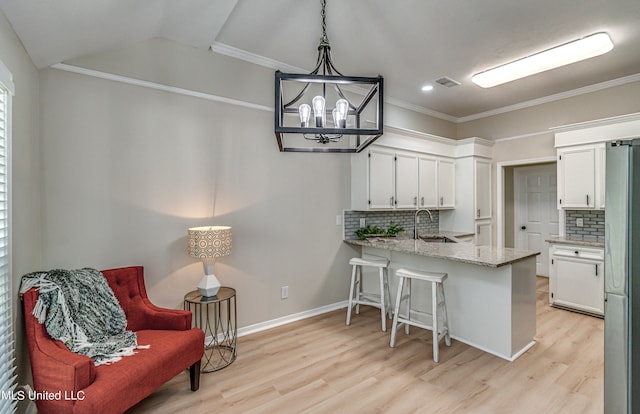 kitchen with kitchen peninsula, decorative backsplash, white cabinets, stainless steel refrigerator, and pendant lighting