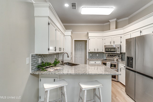 kitchen featuring crown molding, a breakfast bar, light stone countertops, and stainless steel appliances