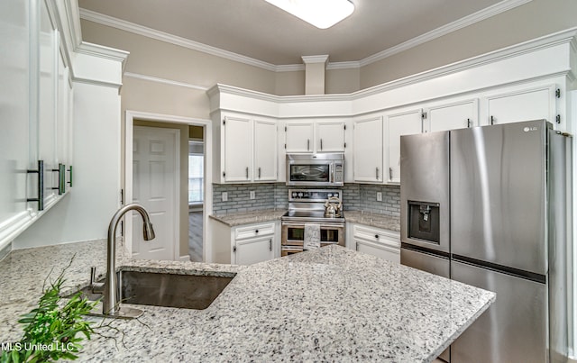 kitchen featuring appliances with stainless steel finishes, sink, white cabinets, light stone counters, and ornamental molding