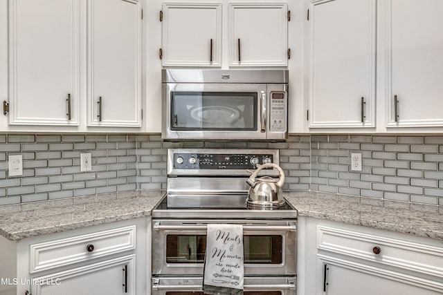 kitchen with light stone countertops, decorative backsplash, white cabinetry, and stainless steel appliances