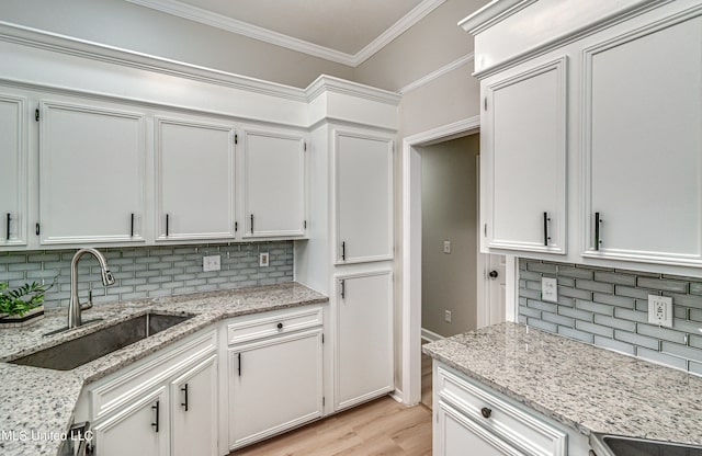 kitchen with white cabinetry, backsplash, and sink