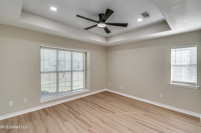 empty room featuring ceiling fan, a raised ceiling, and light hardwood / wood-style flooring