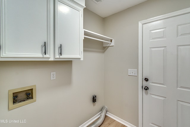 clothes washing area with hookup for a washing machine, light wood-type flooring, and cabinets