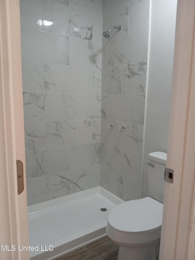 bathroom featuring tiled shower, wood-type flooring, and toilet