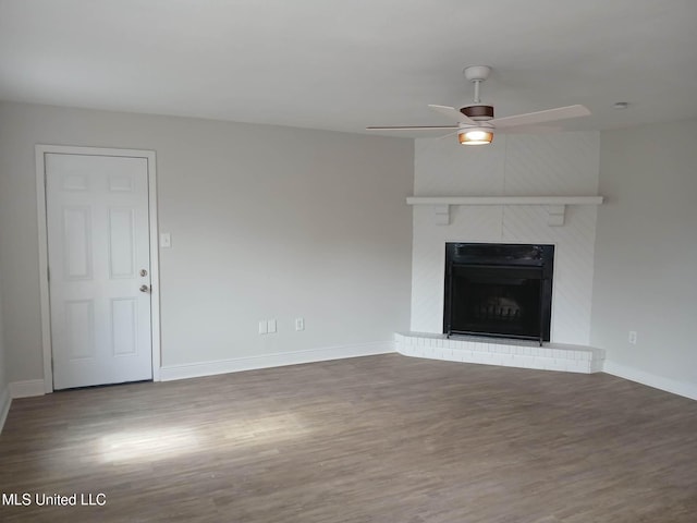 unfurnished living room with a fireplace, dark hardwood / wood-style floors, and ceiling fan