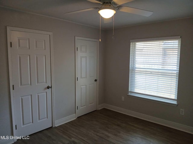 unfurnished bedroom featuring multiple windows, ceiling fan, and dark hardwood / wood-style flooring