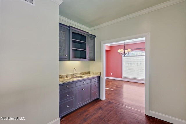 kitchen featuring a notable chandelier, dark hardwood / wood-style flooring, sink, crown molding, and decorative light fixtures