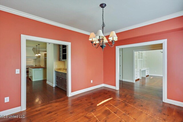 unfurnished dining area featuring ornamental molding, dark wood-type flooring, and a chandelier