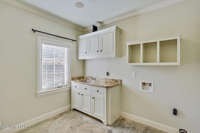 clothes washing area featuring ornamental molding, sink, hookup for a washing machine, and cabinets