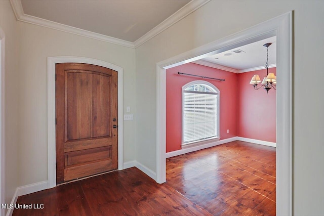 foyer with ornamental molding, dark hardwood / wood-style flooring, and an inviting chandelier