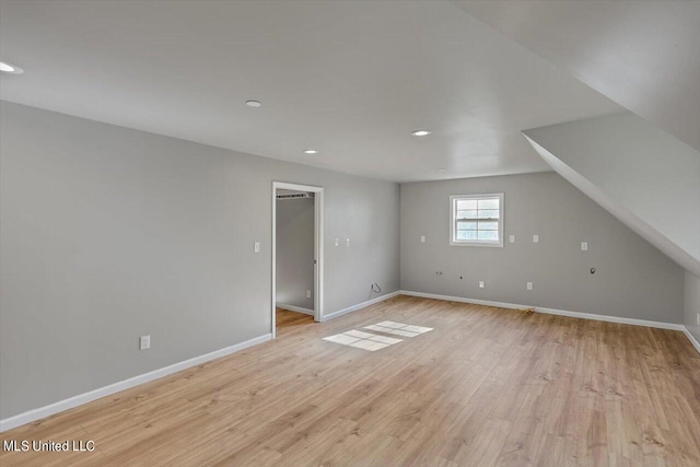 additional living space featuring light hardwood / wood-style floors and lofted ceiling