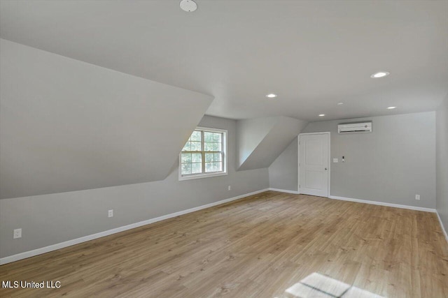 additional living space featuring light hardwood / wood-style flooring, an AC wall unit, and lofted ceiling