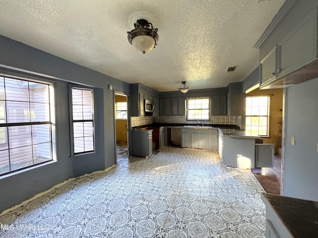 kitchen featuring decorative backsplash, a textured ceiling, gray cabinets, and sink