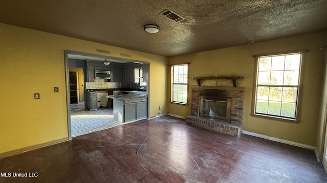 unfurnished living room featuring a fireplace, dark hardwood / wood-style flooring, and a textured ceiling