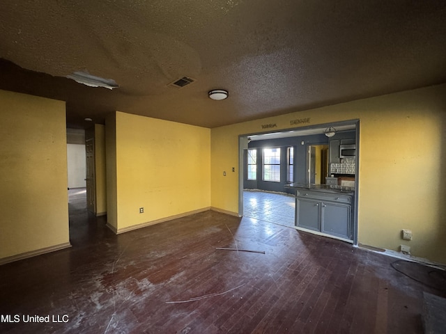 unfurnished living room with dark hardwood / wood-style flooring and a textured ceiling