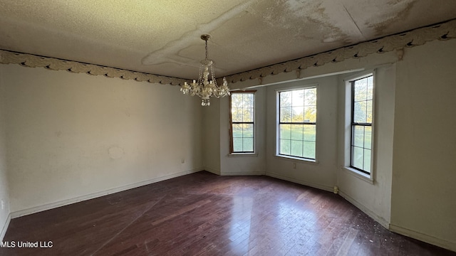 unfurnished dining area with dark wood-type flooring, a textured ceiling, and an inviting chandelier