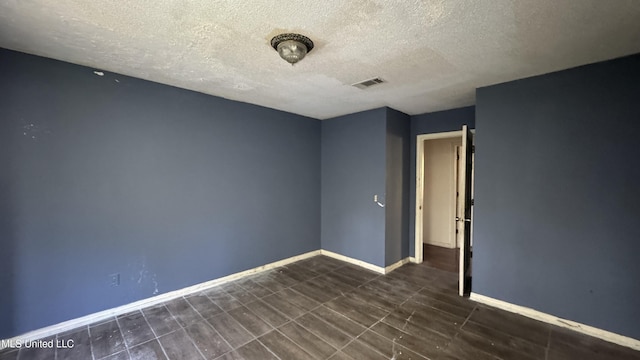 spare room featuring dark wood-type flooring and a textured ceiling