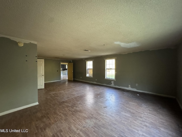 unfurnished living room with a textured ceiling and dark hardwood / wood-style floors